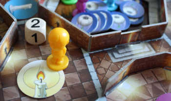 Der gelbe Spieler würfelt eine zwei und zieht über die Treppe zwei Räume weiter.